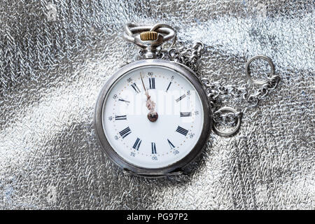 Zwei Minuten vor zwölf Uhr auf alte Taschenuhr silber Stoff Hintergrund Stockfoto