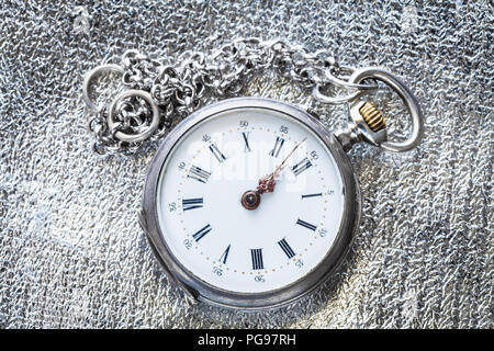 Zwei Minuten vor zwölf Uhr auf antike Taschenuhr silber Stoff Hintergrund Stockfoto