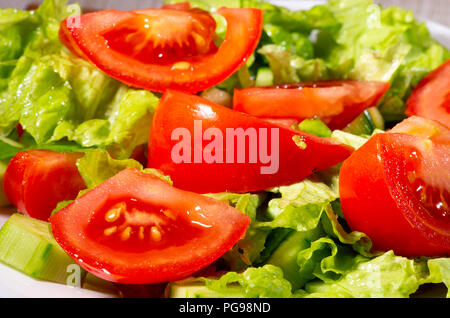 Fragment einer Schale aus Stücken von frischen Gurken, Tomaten, Spinat und Kopfsalat close-up mit blur gemacht. Stockfoto