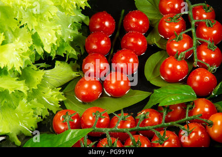 Frisches Gemüse in Wasser zum Waschen, Ansicht von oben auf einem schwarzen Hintergrund. Stockfoto