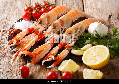Essen Hintergrund frische rohe Scampi, Scampi mit Gemüse, Kräuter und Gewürze in der Nähe auf einem Holztisch. Horizontale Stockfoto