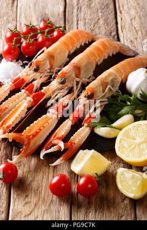 Rohe frische Langusten, Dublin Bay Garnelen, Scampi mit Zitrone, Knoblauch, Tomaten, Kräuter und Gewürze in der Nähe - Auf den Tisch. Vertikale Stockfoto