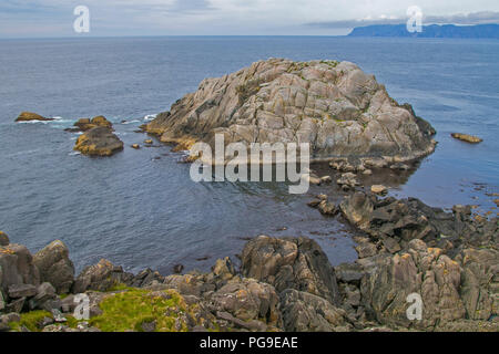 Küsten Norwegen. Ruhige Szene von natürlicher Schönheit. Felsige Küstenlinie, blau bewölkter Himmel, Berge am Horizont. Stockfoto