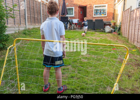 Zwei Jungs spielen Fußball in einem Garten auf der Rückseite Stockfoto