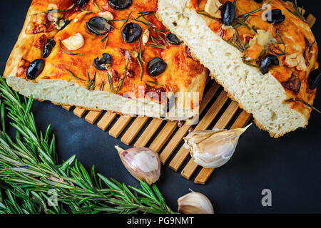 Traditionelle italienische Focaccia mit Oliven, Knoblauch und Rosmarin, selbstgebackenes Brot aus der Nähe Stockfoto