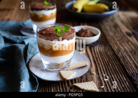 Traditionelle Rezepte Fleisch Dessert mit Karamell, Banane, Biscuit Krümel und Sahne im Glas Tassen serviert. Stockfoto