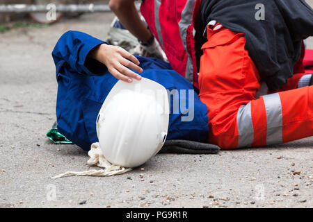 Sanitäter helfen ein Arbeitnehmer nach dem Fall auf einer Baustelle. Schulung in Erster Hilfe. Stockfoto