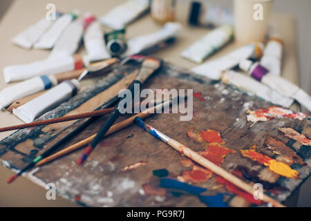 Artist Palette, close-up. Bürsten mit Farben, verschiedene Werkzeuge des Künstlers in der Unordnung. Kreative Werkstatt, Malerei, Kunst Stockfoto