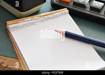 Notizbuch aus Papier und Bleistift mit Taschenrechner auf Tisch Stockfoto
