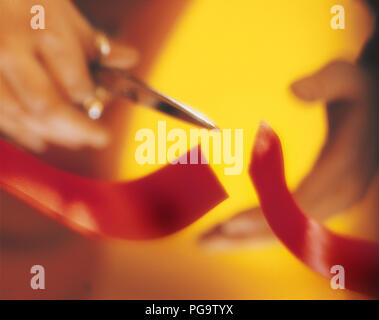 Eine Hand mit der Schere schneiden ein rotes Band. Stockfoto