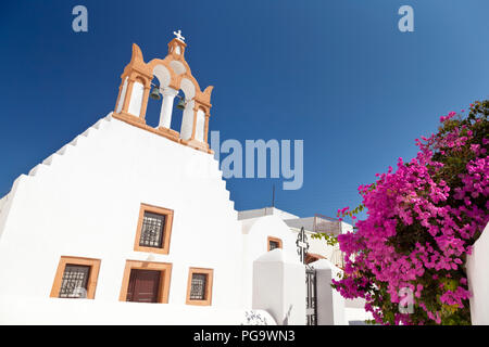 Eine Kirche in Emborio mit bunten Bougainvillea in Santorini. Stockfoto