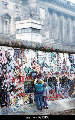 Westdeutsche Kinder versuchen, Chip, ein Stück der Berliner Mauer als Souvenir. Ein Teil der Mauer wurde bereits am Potsdamer Platz abgerissen. Stockfoto