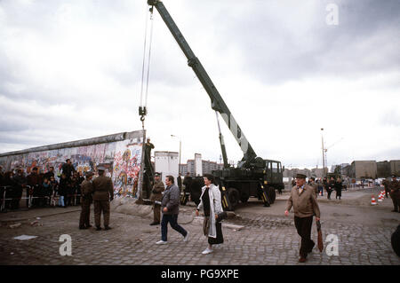 Berliner Mauer 1989 - Ost-berliner überqueren auf den Westen als ein Kran ist die Berliner Mauer am Potsdamer Platz zu demontieren. Stockfoto