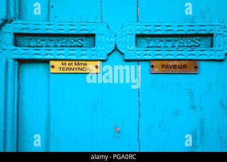 Helle blaue Türen mit Letter Box Klappen mit Namensschilder in Messing in einem alten Mietshaus in Lille, Frankreich Stockfoto