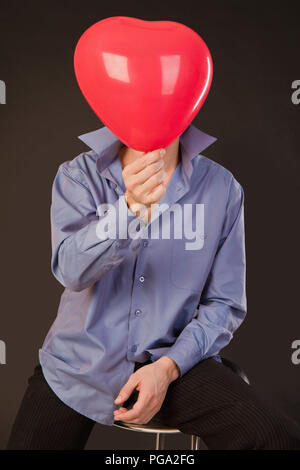 Kerl hält einen Ballon in der Form von Herzen Stockfoto