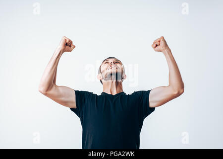 Hübscher junger Mann mit Armen Erfolge feiern Stockfoto