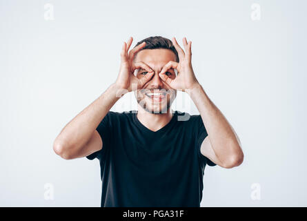 Die jungen Kreativen Menschen, die Finger in die Nähe von Augen wie eine Brille. Spaß-Konzept Stockfoto