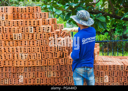 CHIANG MAI, THAILAND - 25. August 2018 - Bauarbeiter nimmt Terrakotta Ziegel aus dem Stapel an einer Baustelle in Chiang Mai, Thailand Stockfoto