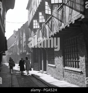 1950, historische, Damen zu Fuß durch die shambles, York, England, UK, einem alten engen gepflasterten Gang, die in den mittelalterlichen Zeiten war eine Straße der Metzger. Stockfoto
