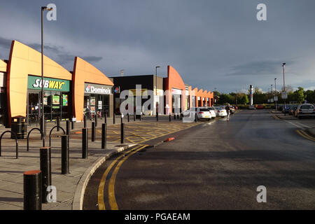 Die verschiedenen bunten Geschäften, Imbissbuden und Restaurants im Onyx Retail Park, Wath auf Dearne, Yorkshire in einem Sturm Cloud Nachthimmel Stockfoto