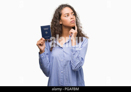 Junge Hispanic woman holding Passport Deutschlands ernsten Gesicht denken über Frage, sehr verworrene Vorstellung Stockfoto