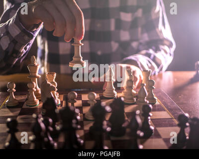 Junge männliche Großmeister hand nächste Bewegung Schach spielen in dunklen Platz auf einem Turnier Stockfoto