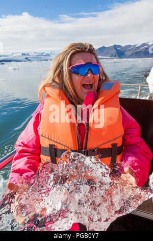 Schöne, reife Frau Spaß heben ein Stück Eisberg auf dem Schiff in der Lagune von Jokulsarlon Stockfoto