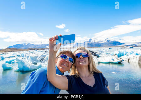 Zwei weibliche Touristen eine selfie mit einem Smart Phone in der eisberge Lagune von jokulsarlon Stockfoto