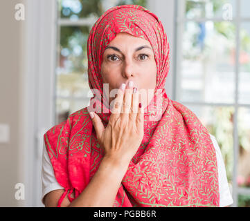 Im mittleren Alter muslimische Frau mit Kopftuch bedecken den Mund mit der Hand mit Schande für den Fehler, den Ausdruck von Angst erschüttert, die in der Stille Angst, geheime Konzept Stockfoto