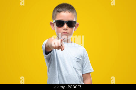 Dunkelhaarige kleine Kind eine Sonnenbrille mit dem Finger an die Kamera und an Sie gerichtet, Handzeichen, positiv und zuversichtlich Geste von vorne Stockfoto