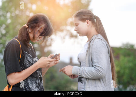 Zwei Mädchen mit Mobiltelefonen in ihren Händen, das Konzept von Freundschaft und Kommunikation Stockfoto