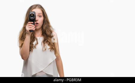 Junge blonde Frau mit Super 8 video kamera Angst im Schlag mit einer Überraschung konfrontiert, ängstlich und aufgeregt mit Angst Ausdruck Stockfoto