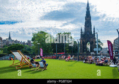 Edinburgh, Großbritannien - 27 Juli, 2018: die Menschen genießen die Sonne auf Liegestühlen in der Nähe von Scott Monument an der Princes Street in Edinburgh auf einen heißen Sommer Stockfoto