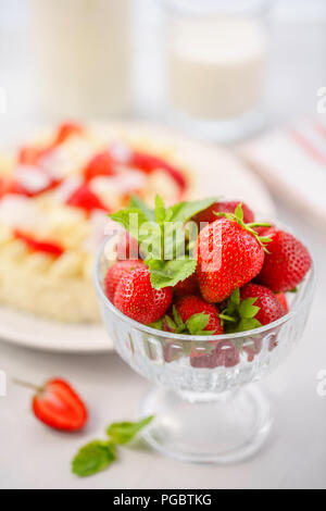 Fokus auf Erdbeeren. Zarte strawberry Cheesecake mit Kokosnuss. Leckere hausgemachte Kuchen mit frischen Beeren auf Leuchtkasten. Stockfoto