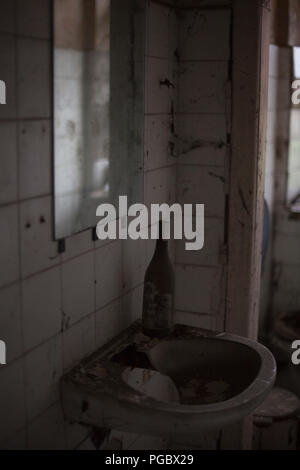 Flasche Wein auf einem defekten Spüle Stockfoto