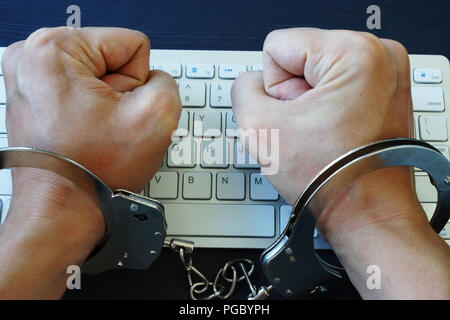 Die Hände in den Handschellen, über die Tastatur. Zensur im Internet oder Hacken. Stockfoto