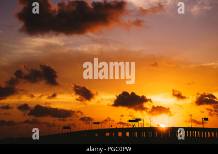 Silhouette eines langen Causeway Road im Abstand während der dramatischen Sonnenuntergang Stockfoto