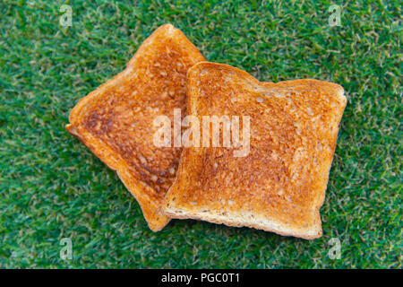 Getoastetes Brot auf dem grünen Gras Hintergrund Stockfoto