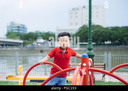 Wenig asiatischen Jungen Reiter ein Schwingen und freut sich Stockfoto