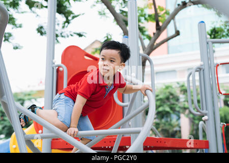 glückliche kleine Junge Klettern am Kinderspielplatz Stockfoto