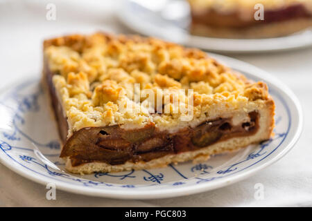 Großes Stück Deutschen selbstgemachten Pflaumenkuchen mit bröckelt auf einer Platte Stockfoto