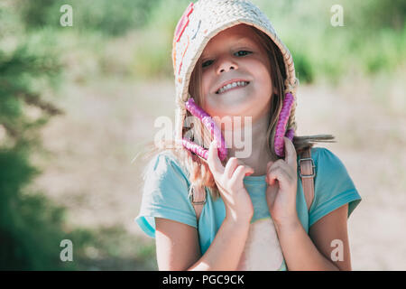 Lächelnd kleine blonde Mädchen spielt mit einem Korb in Ihrem Kopf Stockfoto