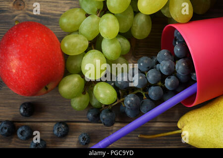Mischung aus saftigen Sommer Früchte und Beeren. Birne, Apfel, grüne und blaue Trauben, Heidelbeeren auf Grau rustikal Holz Hintergrund Platz für Text Stockfoto