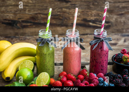 Gesunde, frische Smoothies und Obst auf rustikalen Holzmöbeln Hintergrund Stockfoto
