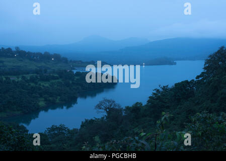 Ruhigen Landschaft in der Dämmerung mit einem See am Bhandardara auch als Wilson Dam mit dichtem Wald und Berge im Nebel Monsun Atmosphäre und Lichter bekannt Stockfoto