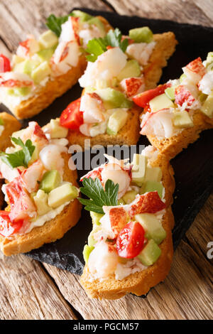 Leckere Toasts mit Hummer, Avocado, Tomate und Frischkäse close-up auf dem Tisch. Vertikale Stockfoto