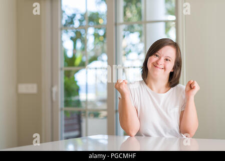 Down Syndrom Frau zu Hause feiern überrascht und für den Erfolg mit erhobenen Armen und offenen Augen überrascht. Sieger Konzept. Stockfoto