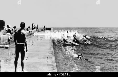 Kalifornien Surfers fangen eine Welle entlang der Newport Harbor Jetty in der Corona Del Mar in den frühen 1930er Jahren. Diese berühmte Stelle im Surf Geschichte war die Heimat der Corona Del Mar Surfboard Verein, 1928 gegründet mit Mitgliedern einschließlich Hawaii Duke Kahanamoku, Redondo Tom Blake, Gen 'Tarzan' Smith, und Gerard und Kunst Vultee der Los Angeles Athletic Club. Es war auch einer der ersten surfen Meisterschaften auf dem US-amerikanischen Festland, die Pazifikküste Surfboard Meisterschaft, die 1928 begann. Stockfoto