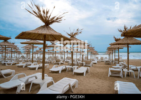 Liegestühle mit Stroh Schirme an einem schönen Strand Stockfoto