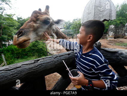 Bangkok, Thailand. 24 Aug, 2018. Ein Junge touch eine Giraffe im Dusit Zoo in Bangkok, Thailand am 24. August 2018. Zoo-goers haben mehr Zeit, sich zu verabschieden Tiere als Dusit Zoo als Einsendeschluss zu sagen, wird von Ende dieses Monats bis 30. September verschoben, 2018 nach 80 Jahren in Betrieb. Credit: chaiwat Subprasom/Pacific Press/Alamy leben Nachrichten Stockfoto